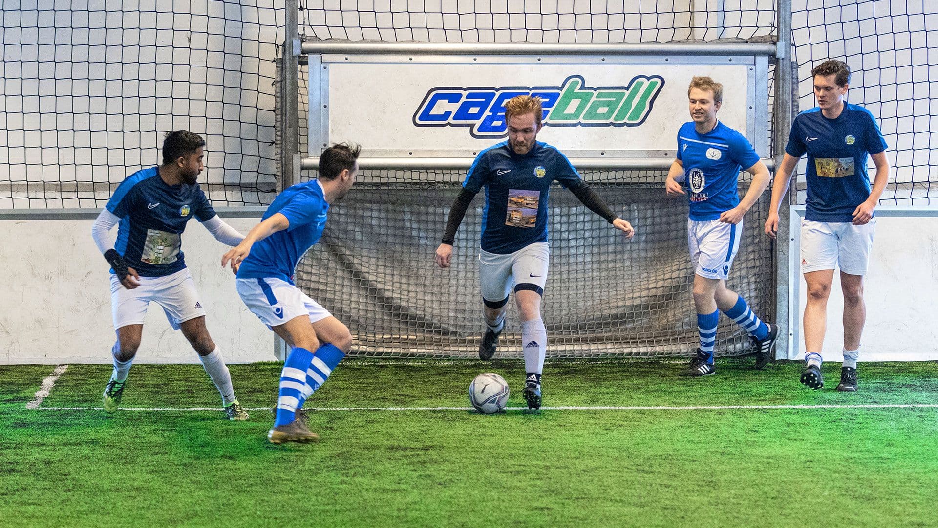 Fotballspill foran mål, inne på Cageball Rosten.