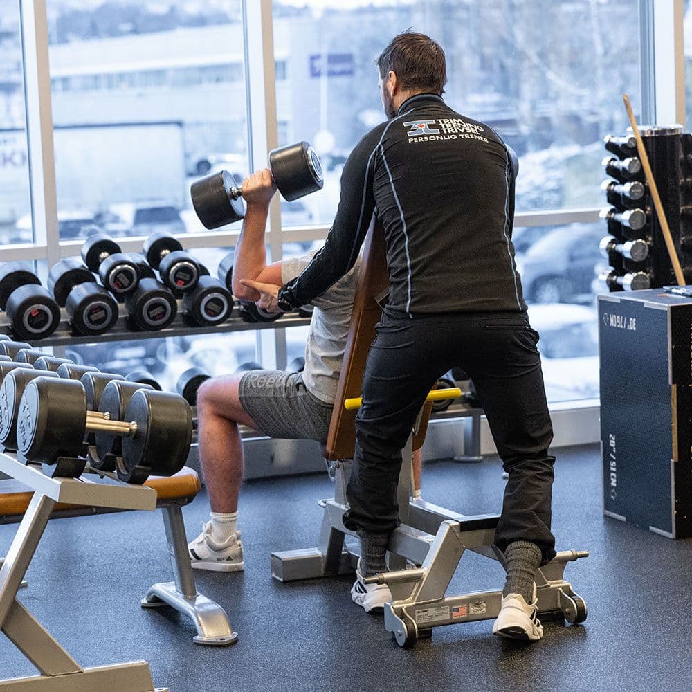 Personlig trener assisterer styrketrening på 3T-Leangen.
