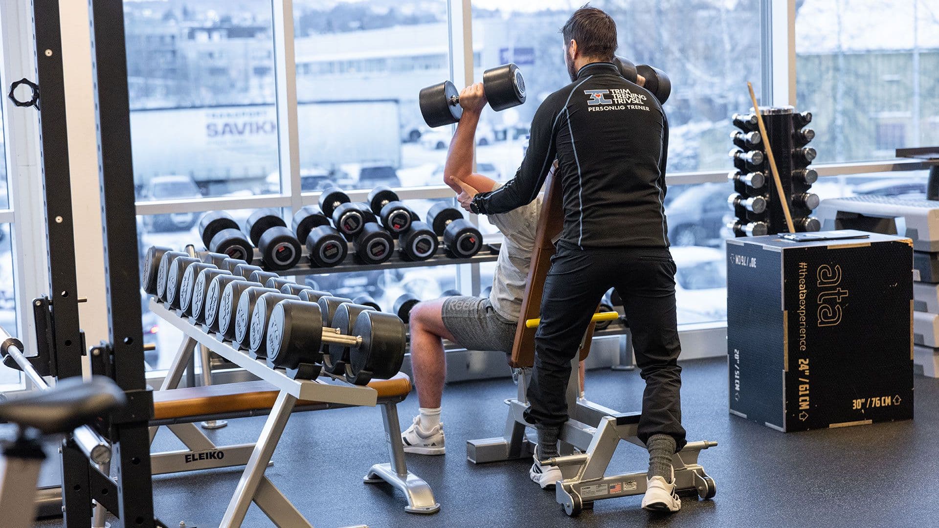 Mann løfter manualer, med hjelp fra personlig trener på 3T-Leangen.